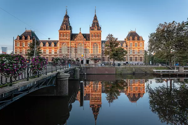 Das Rijksmuseum in Amsterdam von der Sonne beleuchtet, davor ist Wasser.