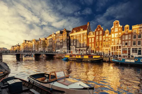 Alte bunte Grachtenhäuser reihen sich an der Gracht, im Vordergrund kleine Fischerboote.