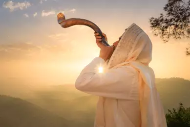 Jüdischer Mann mit Shofar in einer Landschaft im Sonnenuntergang