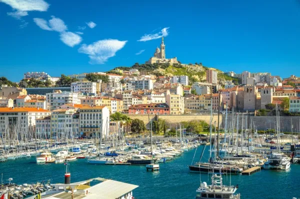 Marseille Blick auf den Yachthafen von Marseille, im Hintergrund thront eine Kathedrale auf einem Berg.