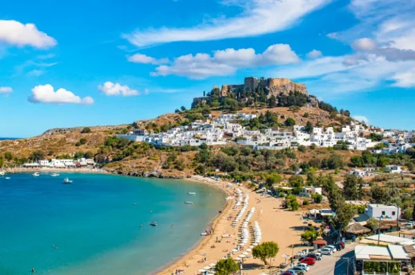 Rhodos Ein Berg thront an der Küste von Rhodos darunter weiße kleine Häuser und türkisblaues Meer.