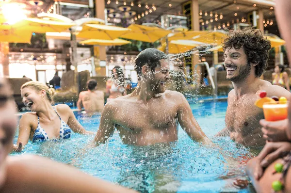 Badespaß und Erfrischung im Poolbereich an Bord von Costa Kreuzfahrten Fröhliche Reisende genießen ein erfrischendes Bad im überdachten Pool an Bord eines Kreuzfahrtschiffs von Costa bei sommerlicher Atmosphäre.