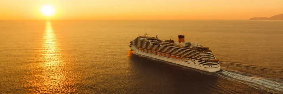 Sonnenuntergang auf See: Costa Kreuzfahrtschiff steuert in das Abendrot Ein modernes Kreuzfahrtschiff von Costa Kreuzfahrten fährt bei goldenem Sonnenuntergang auf ruhigem Meer.