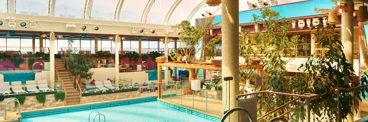 Entspannung im La Spiaggia Beach Club an Bord von Costa Kreuzfahrten Lichtdurchfluteter Innenpool-Bereich mit mediterraner Bepflanzung, Sonnenliegen und überdachtem Glasdach an Bord eines Costa-Schiffs.