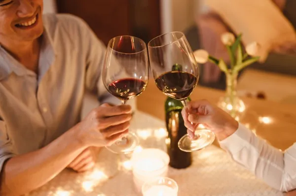 Ein Pärchen stößt mit zwei Gläsern Wein an einem hübsch gedeckten Tisch an.