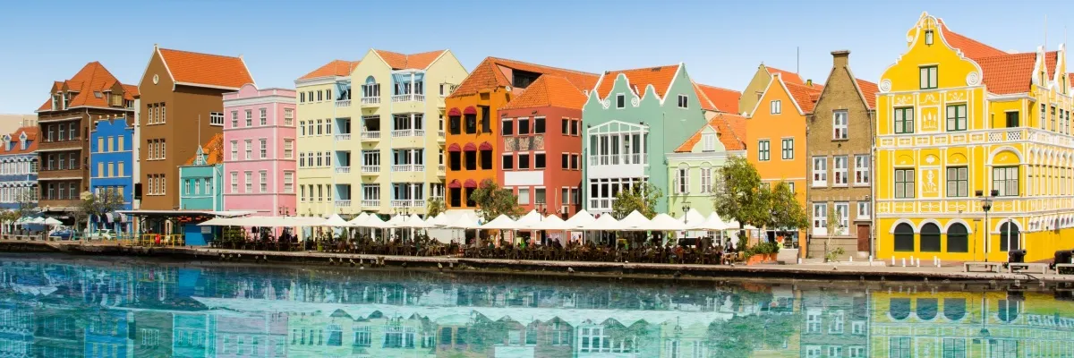 Willemstad ist die Hauptstadt von Curaçao, einer karibischen Insel und fällt durch die bunten Häuser direkt am klaren Wasser auf.