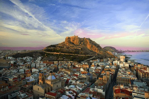 Ein Berg ragt hinter der Stadt Alicante hervor.