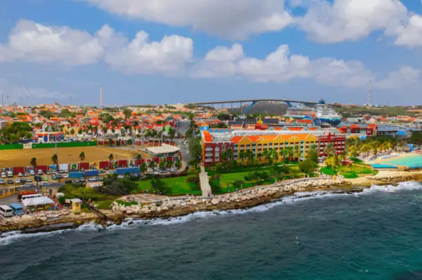 Blick auf den Kreuzfahrthafen von Willemstad auf Curaçao. Hafen von Willemstadt mit bunten Häusern an der Waterfront und Kreuzfahrtschiff im Hintergrund.