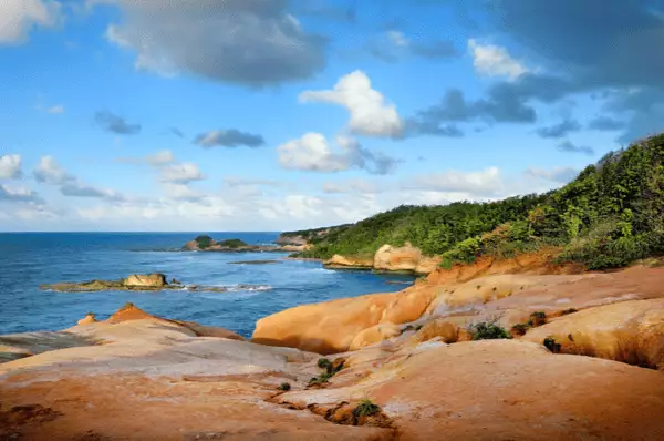 Felsiger Strand auf Dominica Roter Felsstrand an einem bewölkten Tag auf Dominica.