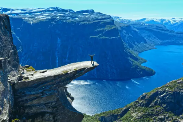 Majestätisch: Die Trolltunga hoch über dem Hardangerfjord Ein Mann steht auf der riesigen Felszunge Trolltunga und bewundert die atemberaubende Aussicht auf den Hardangerfjord.