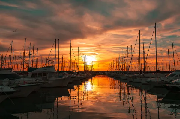 Romantischer Sonnenuntergang im Hafen von Civitavecchia mit vielen Segelbooten und Yachten im Wasser.