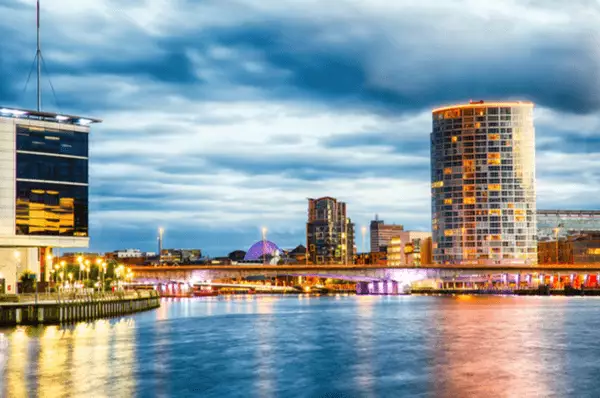 Leuchtende Brücke und Gebäude in Belfast bei Nacht mit dem Fluss Lagan