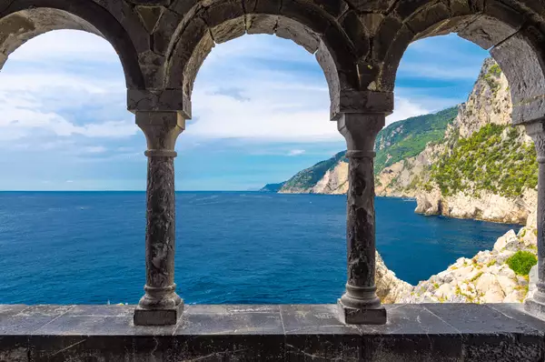 Blick durch die Bogenkolonnade der Chiesa San Pietro auf die felsige Küste bei Portovenere, in der sich auch die Grotta di Lord Byron befindet.
