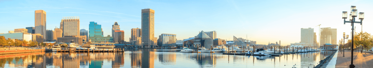 Blick auf den Inner Harbor im Stadtzentrum von Baltimore mit seiner Skyline mit Hochhäusern, die sich im Wasser widerspiegeln.