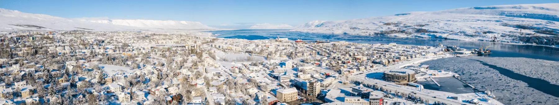 Blick aus der Vogelperspektive auf das schneebedeckte Akureyri an Islands Küste