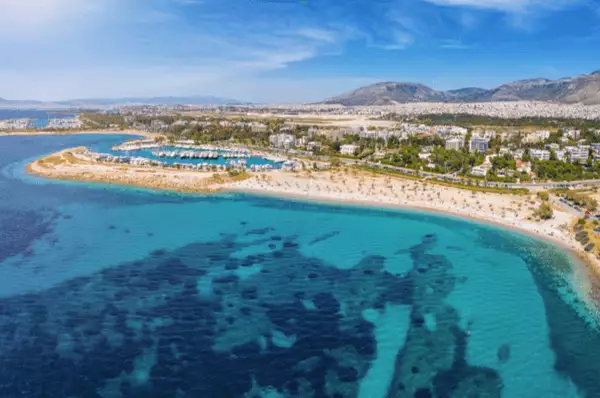 Luftbild des Strands von Glyfada mit türkisblauem Meer und blauem, leicht bewölktem Himmel.