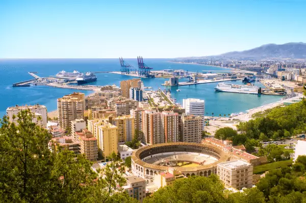 Ansicht von Málaga mit Stierkampfarena, unzähligen Hochhäusern und Hafen mit dem Meer im Hintergrund, Spanien