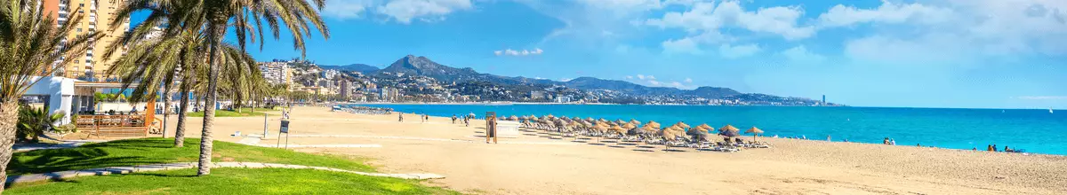 Panoramasicht auf den Strand von Malagueta in Malaga mit Palmen, Badegästen und türkisem Meer