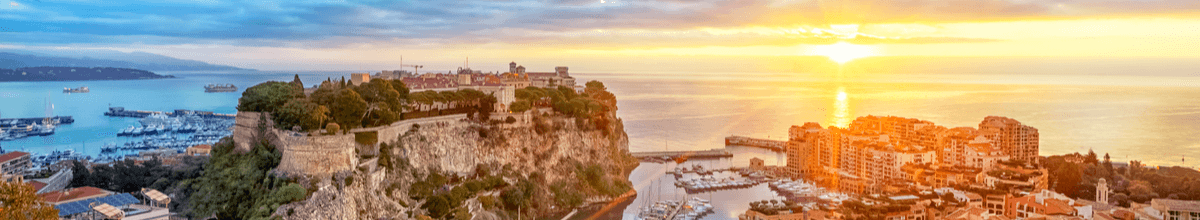 Sonnenaufgang in Monaco Aussicht auf den Hafen Fontvieille mit vielen Jachten und dem Felsen von Monaco mit der Altstadt im Hintergrund