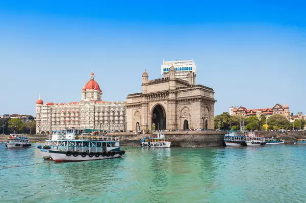 Das Tor Indiens am Hafen von Mumbai Das Tor Indiens am Hafen von Mumbai mit vielen Booten und strahlend blauem Himmel und türkisem Wasser mit Häusern im Hintergrund.