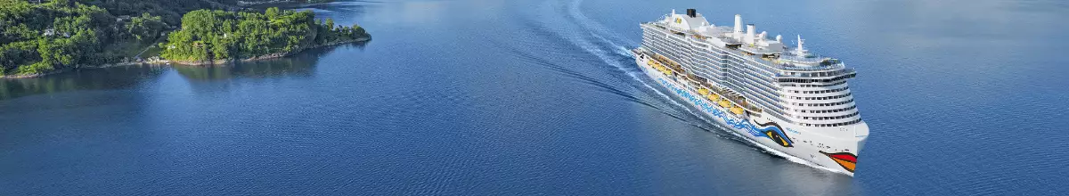 Seitliche Ansicht von AIDAcosma auf dem Wasser vor einer Insel.
