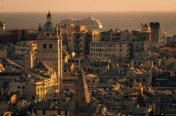 Kreuzfahrthafen Genua: Altstadt-Panorama mit Kreuzfahrtschiff bei Sonnenuntergang Panoramablick im goldenen Abendlicht über die Altstadt von Genua mit historischen Kirchtürmen und einem Kreuzfahrtschiff im Hafen.