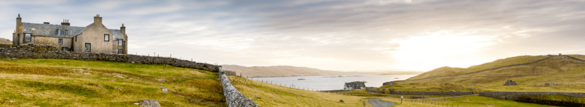 Altes Steinhaus auf einer grünen Graslandschaft mit bewölktem Himmel auf den Shetland Islands, Schottland