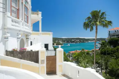 Blick von einer Straße in der höher gelegenen Altstadt auf die Schiffe im Hafen von Menorca.