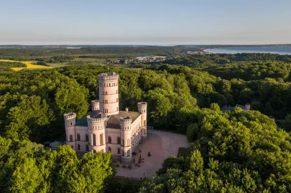 Luftaufnahme des Jagdschlosses Granitz mit dem hohen charakteristischen Mittelturm umrundet von einem Wald auf der Insel Rügen