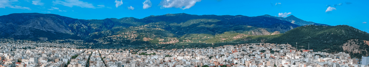 Luftbild über die Stadt Volos mit blauem Himmel und Bergen im Hintergrund in Griechenland