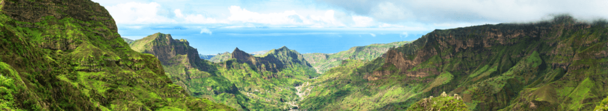 Grüne Berggipfel auf der Insel Santiago mit blauem Himmel und dem Meer im Hintergrund