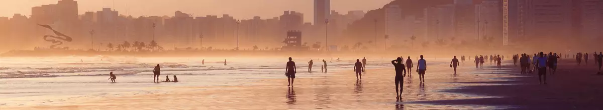 Santos, Brasilien - Strandspaziergang bei Sonnenuntergang mit Silhouetten von Menschen, die am Strand laufen