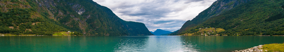 Fjord in Skjolden mit grün-blauem Wasser und einem Berg in Hintergrund, Norwegen