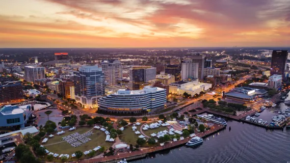 Luftaufnahme von Downtown Norfolk in Virginia bei Sonnenuntergang mit dem Town Point Park am Elizabeth River nahe dem Kreuzfahrthafen.