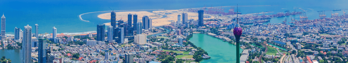 Luftaufnahme von Colombo mit einem Häusermeer und einem Fernsehturm mit Blick aufs Meer, Sri Lanka