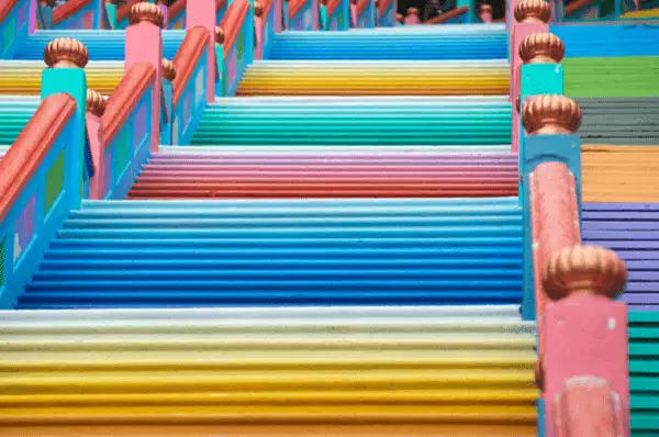 Bunte Treppenstufen in gelb, blau, rot und grün mit blau-rot verziertem Geländer.