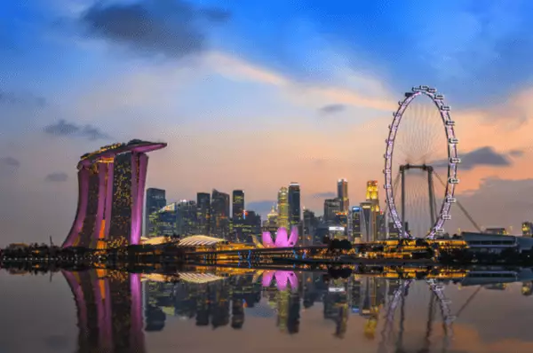 Das Riesenrad Singapore Flyer und die Hochhäuser der Marina Bay City in Singapur bei Nacht.