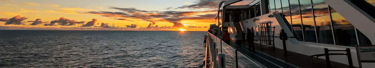 Außendeck von Mein Schiff 1 im warmen Licht des Sonnenuntergangs über dem Meer.
