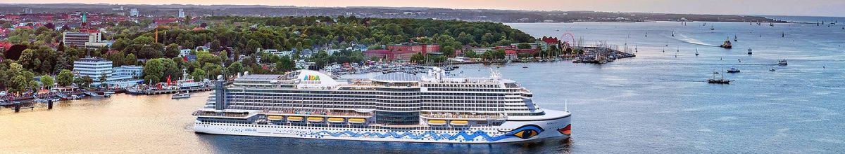 AIDA Kreuzfahrtschiff der Hyperion-Klasse (z.B. AIDAprima) in einem Hafen bei Sonnenuntergang, Symbol für eine unvergessliche Seereise mit der AIDA Flotte.