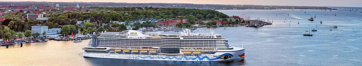 AIDA Kreuzfahrtschiff der Hyperion-Klasse (z.B. AIDAprima) in einem Hafen bei Sonnenuntergang, Symbol für eine unvergessliche Seereise mit der AIDA Flotte.