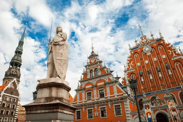 Rathaus Riga, Schwarzhäupterhaus und der St. Roland auf dem Marktplatz mit der Petrikirche im Hintergrund bei leicht wolkigem Himmel