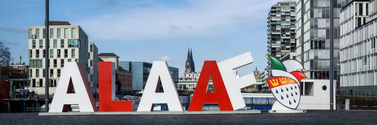 ein großes Schild mit dem Text "Alaaf" in rot und weiß am Rheinufer von Köln. Es ist das Zeichen des Karnevals.