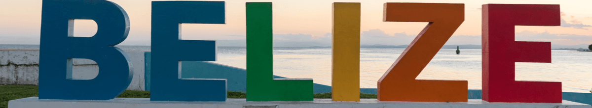 Das Wort Belize steht in bunten Buchstaben in Blau, Grün, Gelb, Orange und Rot vor der Küste des Karibischen Meeres in Belize City.
