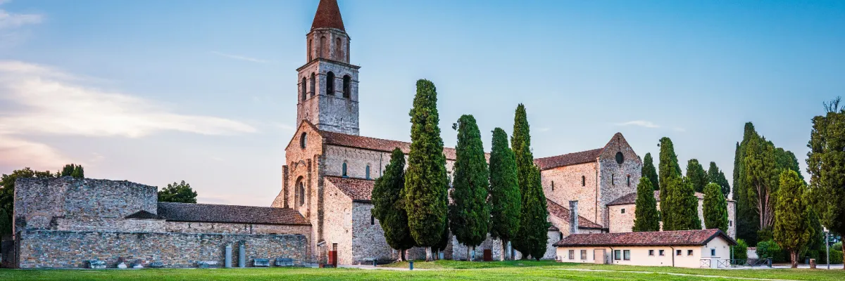 Die historische Basilika von Aquileia mit Glockenturm und antiken Ruinen.