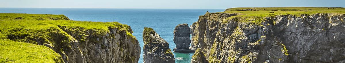 Ein Blick auf verklüftete Felsen mit blauem Meer im Hintergrund an einer abgelegenen Bucht entlang der Pembrokeshire-Küste