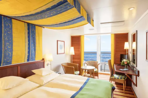 Kabine mit Balkon, Doppelbett, Schreibtisch und Sitzgelegenheit auf AIDAvita