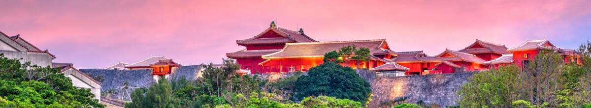 Kulisse der Burg Shuri bei Sonnenaufgang mit rosa Himmel und roten Dächern des Schlosses - Okinawa, Japan