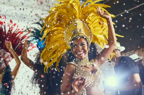 Erleben Sie Karneval in Rio de Janeiro Begeisterte Frau beim farbenfrohen Karneval in Rio de Janeiro, trägt traditionelles Kostüm und tanzt im Konfetti-Regen.