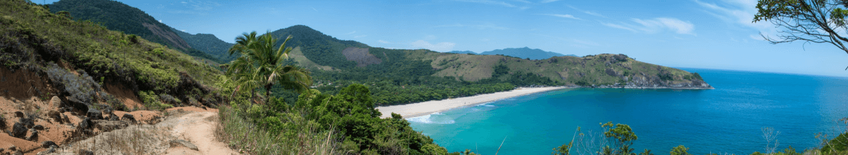 Sandküste an blauem Meer mit Naturpfad durch grüne Wälder