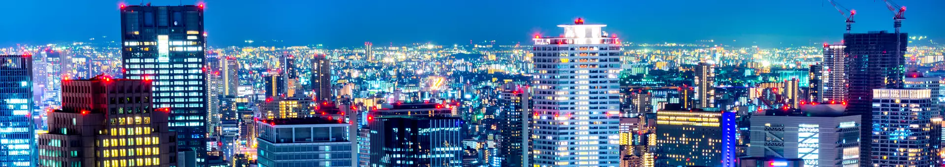 Zur frühen Abendstunde ragen die Hochhäuser der Stadt in den Himmel, alle Häuser erleuchten in Ihren Lichtern